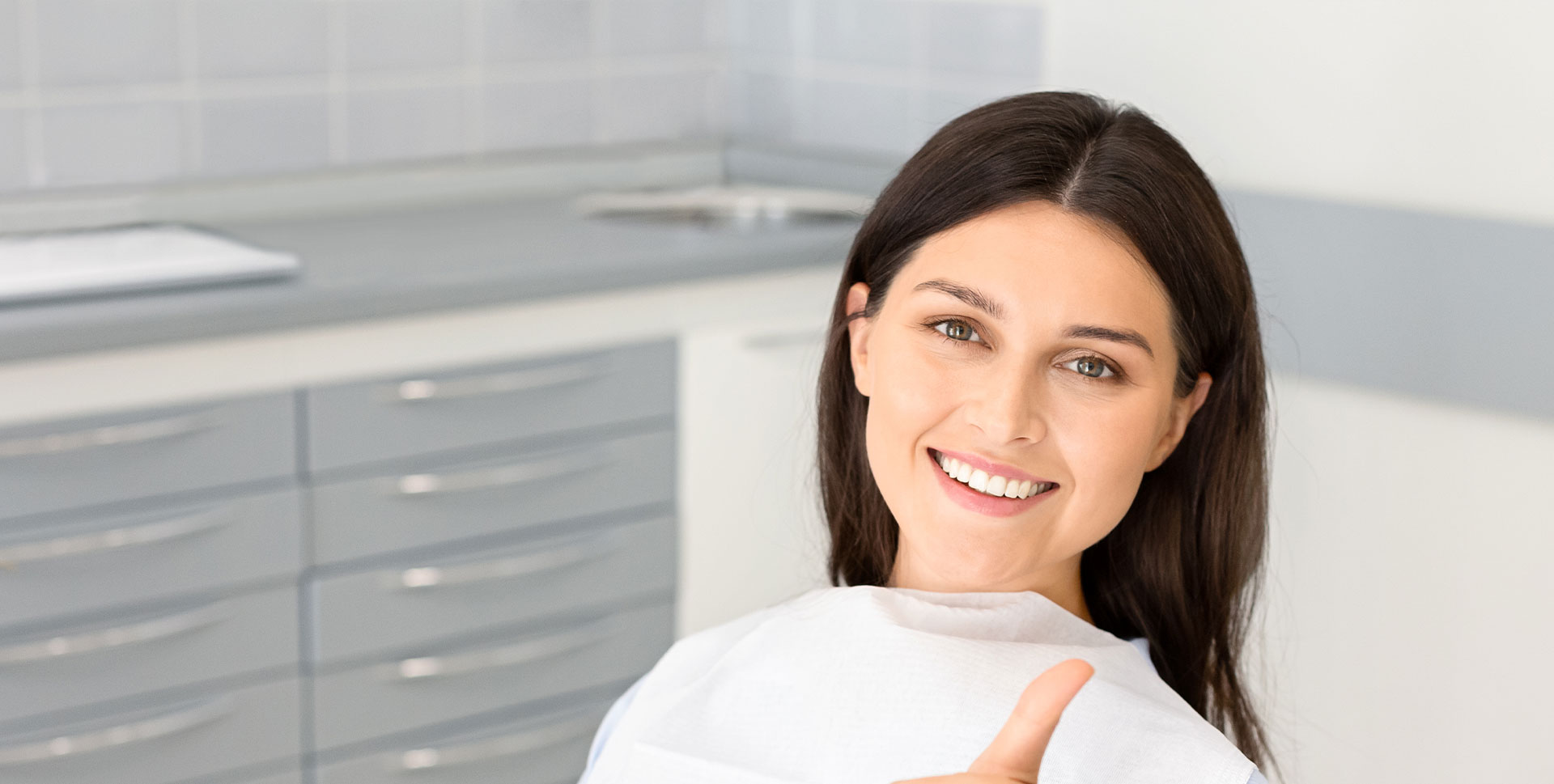 Smiling woman in a dental setting, endorsing dental care services.