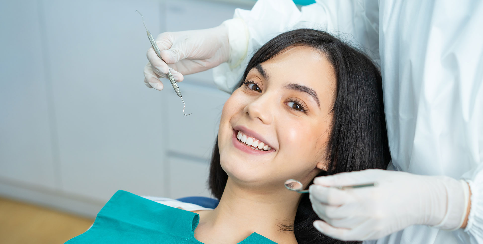 A woman receiving dental treatment, with a dentist performing the procedure in the background.