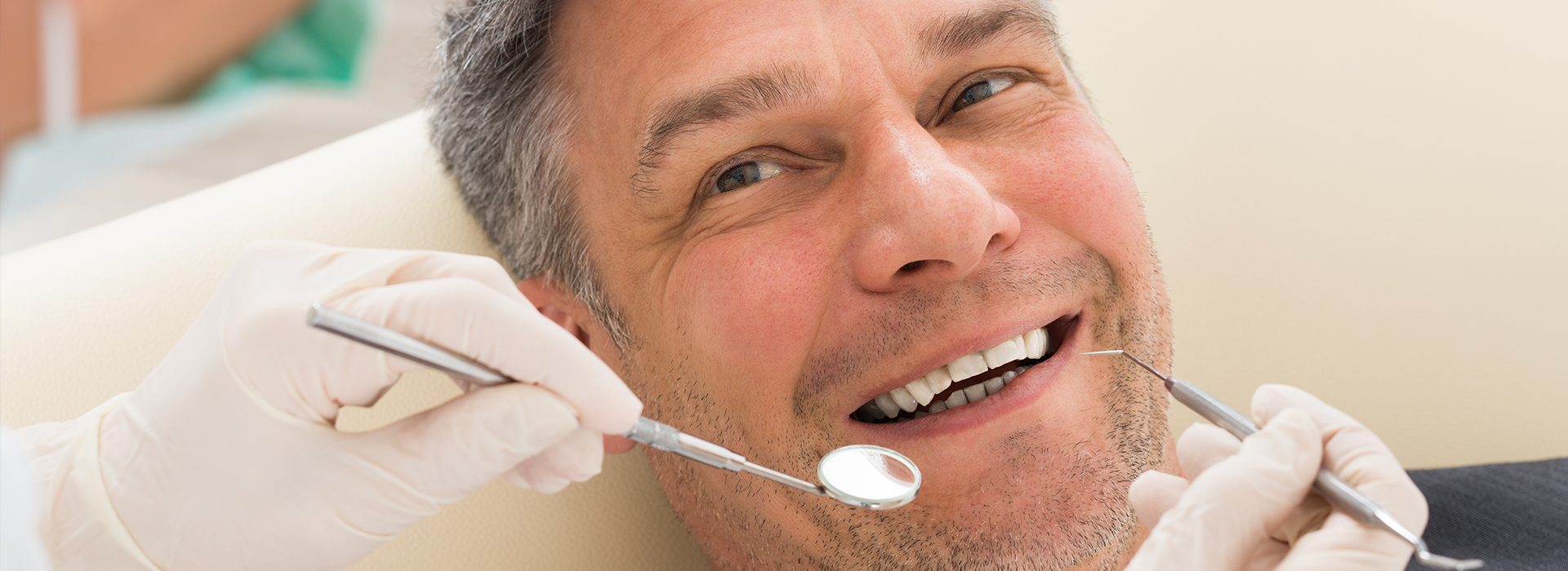 Man in dental chair receiving dental treatment with smiling expression.