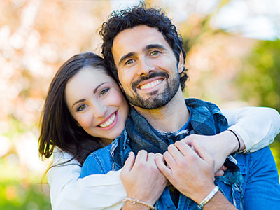 The image shows a man and woman embracing each other, both smiling and appearing happy.