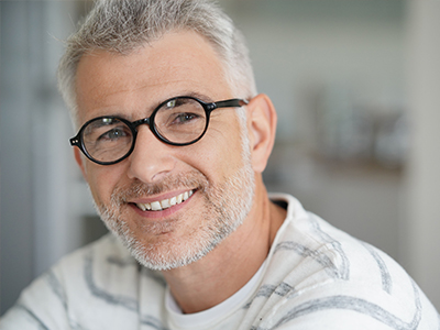 A man with a beard, wearing glasses and smiling at the camera.